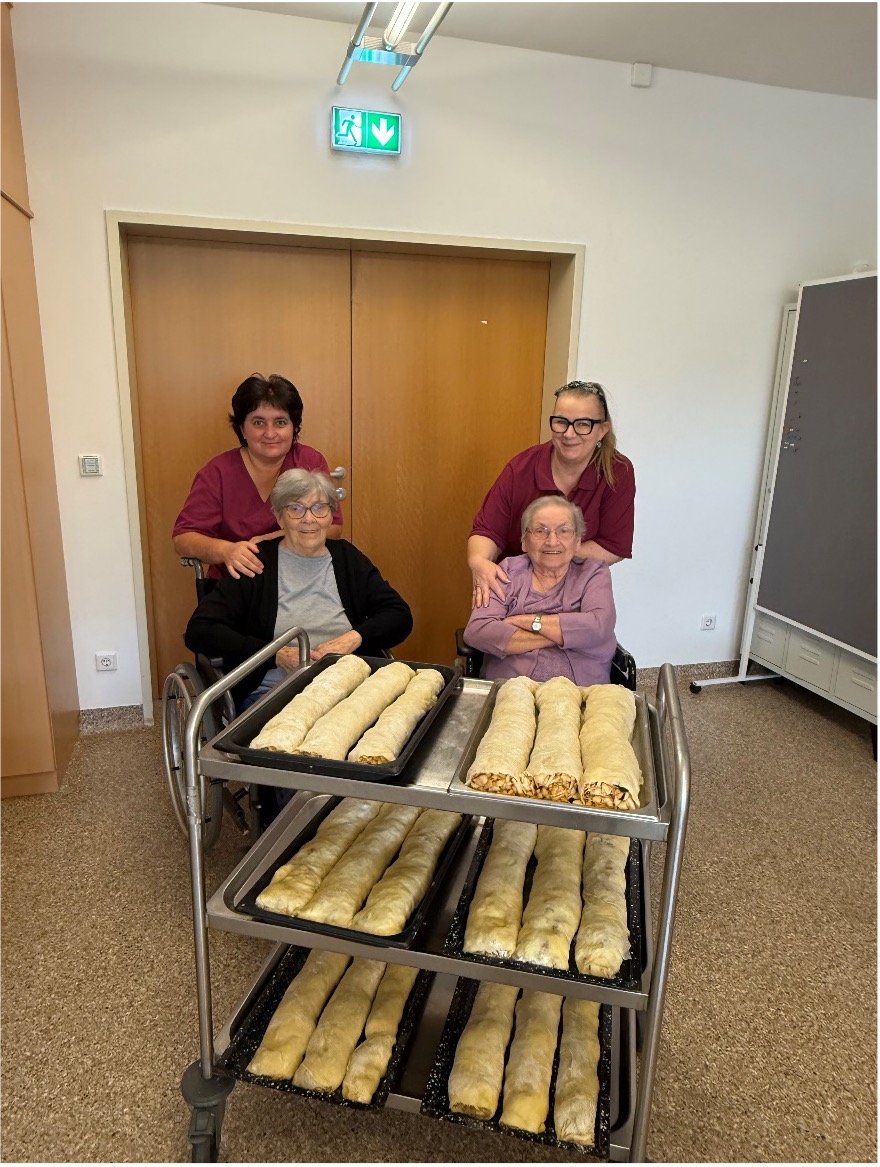 Vier Personen stehen um einen Wagen mit frisch gebackenen Strudel.