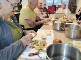 Ältere Menschen schälen Äpfel in einem Gemeinschaftsraum.