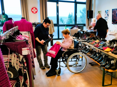 Eine Frau im Rollstuhl erhält Hilfe beim Einkauf von Schuhen.