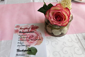 Speisekarte mit Hauptgerichten und einer dekorativen Rose in einer Glasvase.