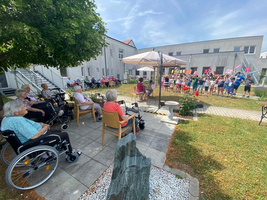 Eine Gruppe von Kindern singt im Garten für ältere Menschen.