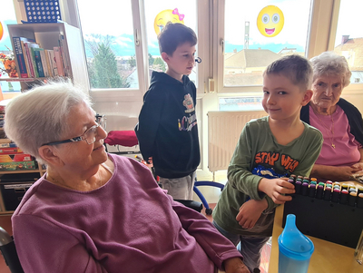 Kinder spielen mit Farben in einem Gemeinschaftsraum mit älteren Menschen.