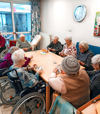 Ältere Frauen sitzen um einen Tisch und spielen Karten.