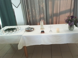 Ein Tisch mit Kerzen, einer Statue und einer Blume in einer Vase.