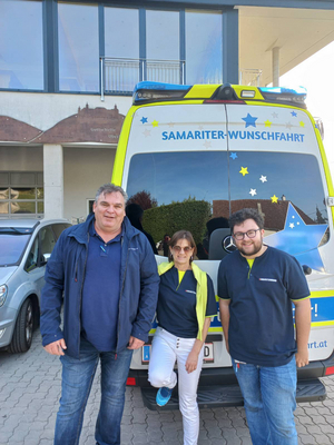 Drei Personen stehen vor einem Einsatzwagen der Samariter-Wunschfahrt.