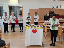 Eine Gruppe von Frauen singt und liest in einem dekorierten Raum.