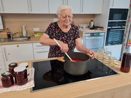 Eine ältere Frau kocht Marmelade in einer modernen Küche.