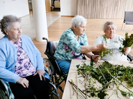 Ältere Frauen gestalten mit Pflanzen und Zweigen ein kreatives Projekt.