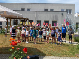 Eine Gruppe Kinder hält bunte Buchstaben hoch und lächelt in die Kamera.