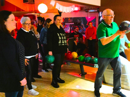 Eine Gruppe Menschen beim Bowlingspielen in einer lebhaften Umgebung.