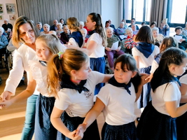 Tanzende Kinder führen eine Aufführung für Senioren in einem Gemeinschaftsraum auf.
