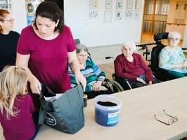 Eine Gruppe von Senioren und zwei Frauen bereitet eine Aktivität mit Erde vor.