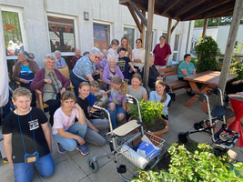 Kinder und Senior:innen sitzen im Schatten 