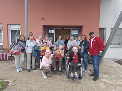 Gruppenfoto von Senioren und Betreuern vor einem Gebäude.
