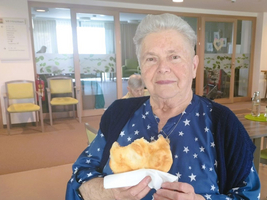 Eine ältere Frau hält ein großes Stück Brot in den Händen.