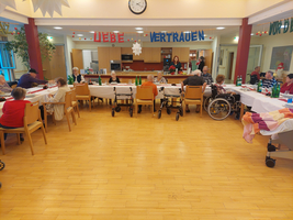 Ältere Menschen sitzen an einem Tisch in einem festlich geschmückten Raum.