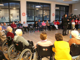 Senioren in Rollstühlen bei einer Veranstaltung in einem Gemeinschaftsraum.