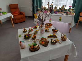 Osterdekoration mit bunten Figuren und Blüten auf einem Tisch.