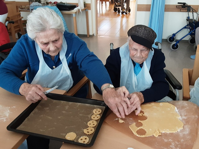 Zwei ältere Frauen backen Plätzchen in einer gemütlichen Umgebung.