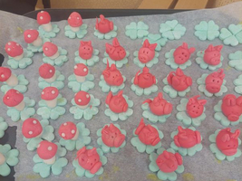 Bunte, essbare Tierfiguren und Blumen aus Zucker auf Backpapier.
