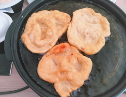 Drei frittierte Teigstücke auf einer heißen Platte.