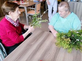 Ältere Frauen sitzen um einen Tisch mit Pflanzenmaterial für Bastelarbeiten.