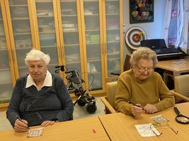 Zwei ältere Frauen sitzen an einem Tisch und malen Bilder aus.