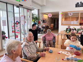 Ältere Menschen und Kinder genießen gemeinsam eine Bastelaktivität in einem Gemeinschaftsraum.