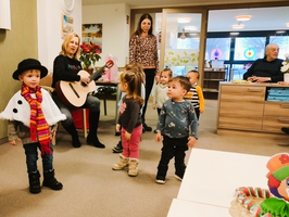 Kinder singen und tanzen, während eine Frau Gitarre spielt.