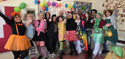 Gruppe von Menschen in Kostümen feiert fröhlich mit Ballons und Dekoration.