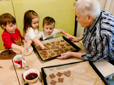Eine ältere Person backt mit drei Kindern Plätzchen.