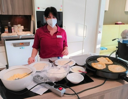 Eine Frau kocht in einer Küche, während Teig und Pfannkuchen vorbereitet werden.