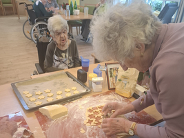 Ältere Frauen backen gemeinsam Weihnachtsplätzchen in einer gemütlichen Umgebung.