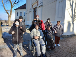 Eine Gruppe von Menschen, darunter ein Rollstuhlfahrer, posiert draußen vor einem Gebäude.