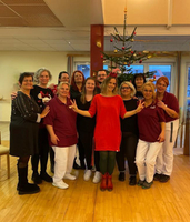 Eine Gruppe von 14 Personen feiert vor einem Weihnachtsbaum.