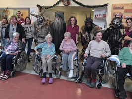 Gruppenfoto mit älteren Menschen in Rollstühlen und Leuten in kostümierten Verkleidungen.