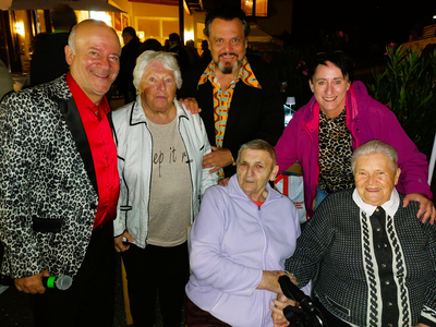 Eine Gruppe von sechs Personen posiert lächelnd für ein Foto bei Nacht.