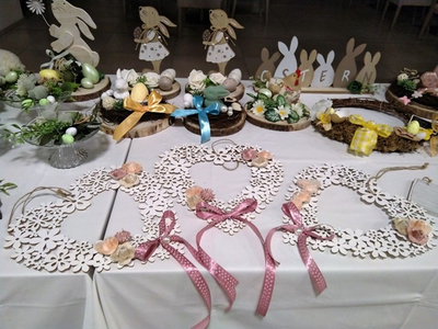 Osterdekoration mit Holzkränzen, Blumen und bunten Schleifen auf einem Tisch.