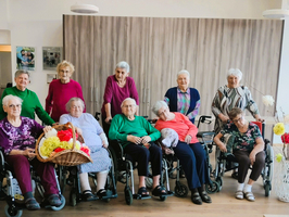 Gruppe von älteren Frauen in Rollstühlen, lächelnd und gemeinsam posierend.