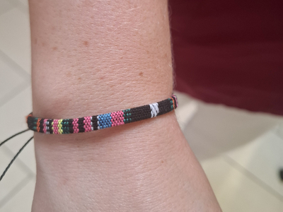 Ein buntes Armband liegt auf einem Handgelenk.