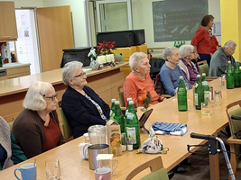 Ältere Frauen sitzen an einem Tisch mit Getränken im Gemeinschaftsraum.