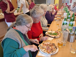 Ältere Frauen genießen gemeinsam Essen an einem Tisch in einem gemütlichen Raum.