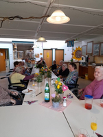 Eine Gruppe älterer Menschen feiert eine Zusammenkunft an einem festlich gedeckten Tisch.