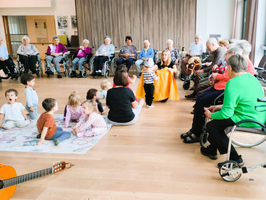 Eine Gruppe von Senioren sitzt mit Kindern in einem Gemeinschaftsraum.