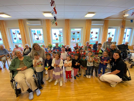 Kinder und Senioren posieren gemeinsam in einem bunten Gemeinschaftsraum.