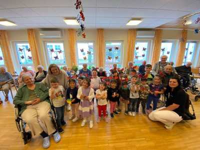 Kinder und Senioren posieren gemeinsam in einem bunten Gemeinschaftsraum.