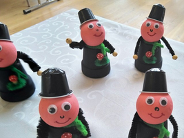 Fünf bunte, fröhliche Figuren mit Hüten und Weihnachtsdekoration stehen zusammen.
