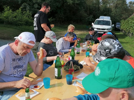Eine Gruppe von Menschen sitzt bei einem Picknick am Tisch und genießt Essen.