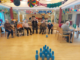 Ältere Menschen spielen Bowling in einem Gemeinschaftsraum.