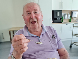 Ein älterer Mann genießt Eiscreme mit Waffeln und lächelt.
